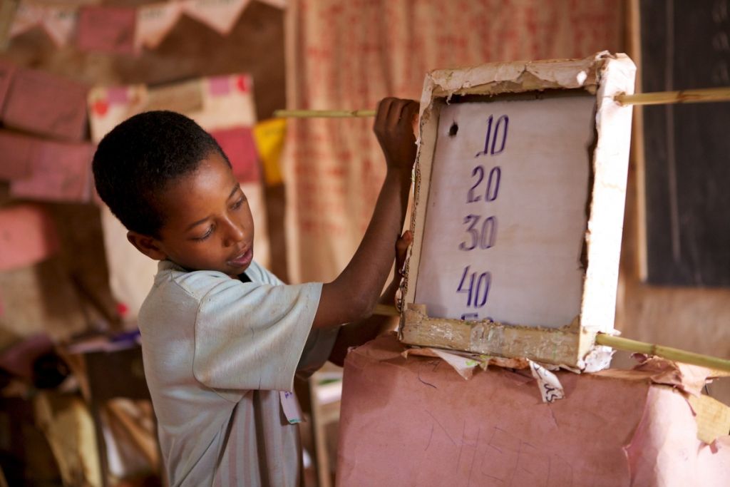 young boy at school using a board to do maths
