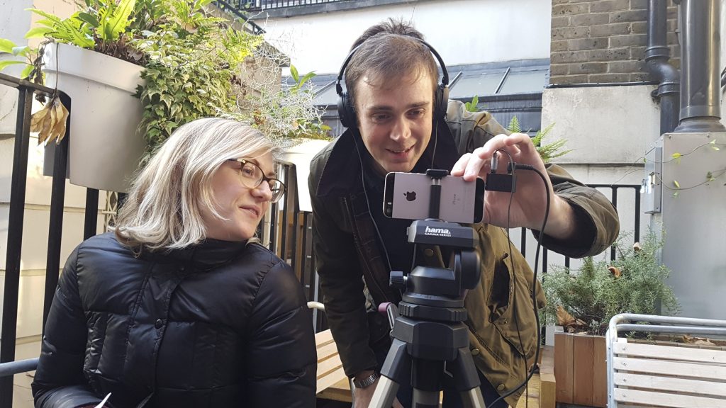 a man and woman using a smartphone on a tripod to conduct an interview
