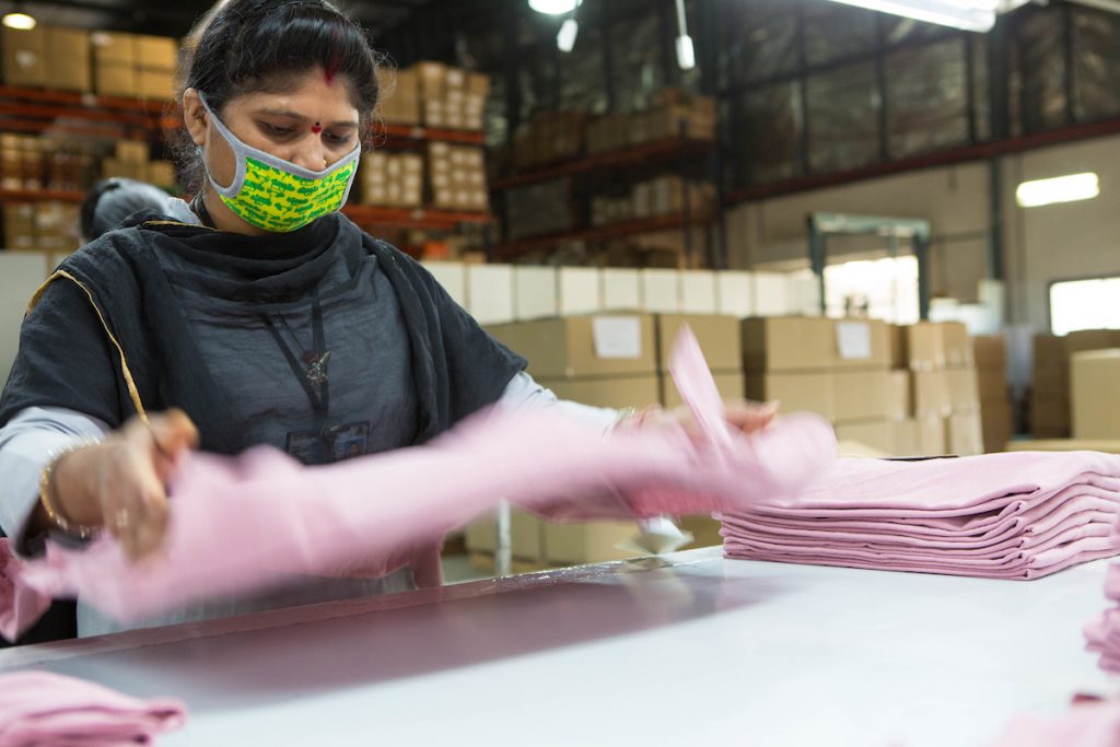 a woman folding t shirts in an organic cotton factory, India